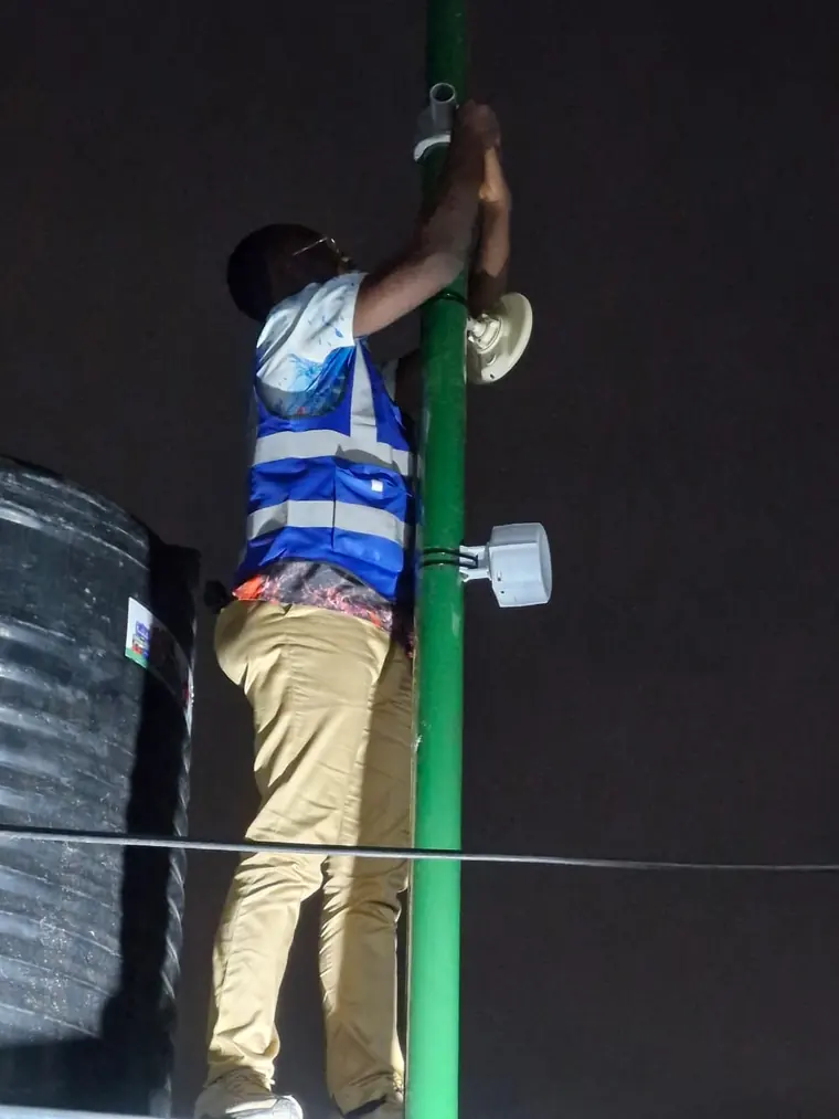 A MulticomIoT technician fitting a device to a mast at night.